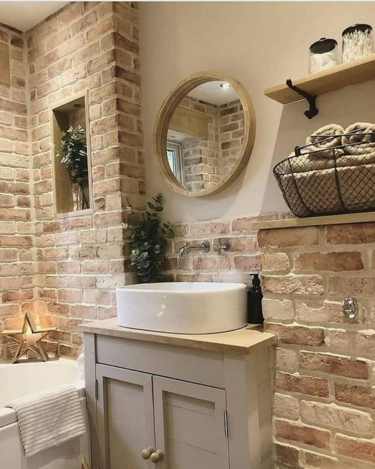 A round wooden mirror mounted on a wall above a white sink and brickwork.