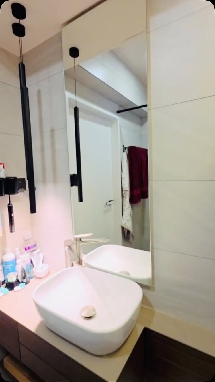 A large rectangular frameless mirror mounted above a white vessel sink in a modern bathroom.