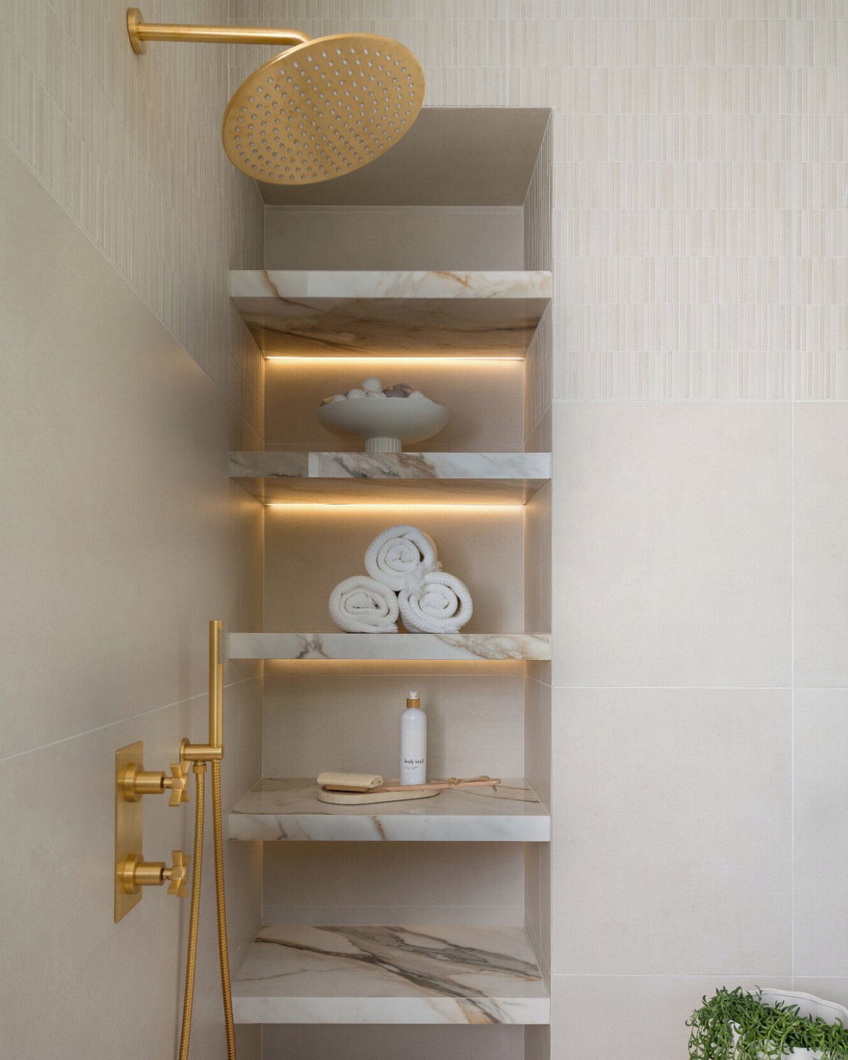 21 Bathroom Shelf Ideas That Make Tight Storage Work Harder 16 Built-in marble shower shelves with warm LED backlighting holding white towels and toiletries.