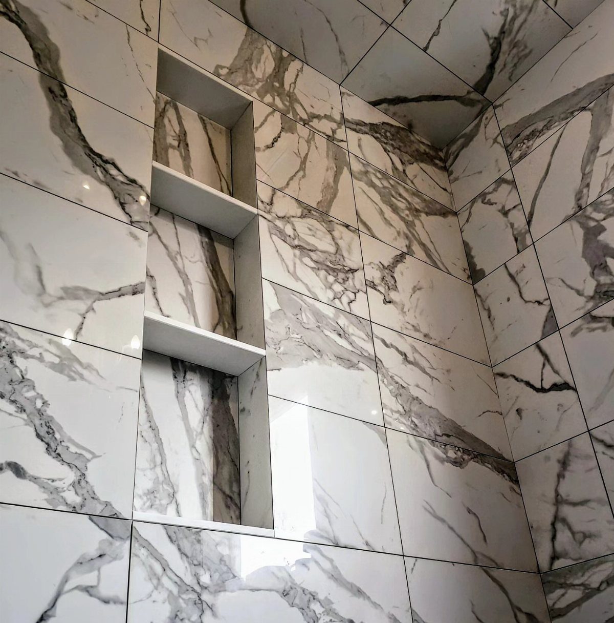 21 Bathroom Shelf Ideas That Make Tight Storage Work Harder 15 Built-in wall niche with three white shelves set into white marble tiled walls.