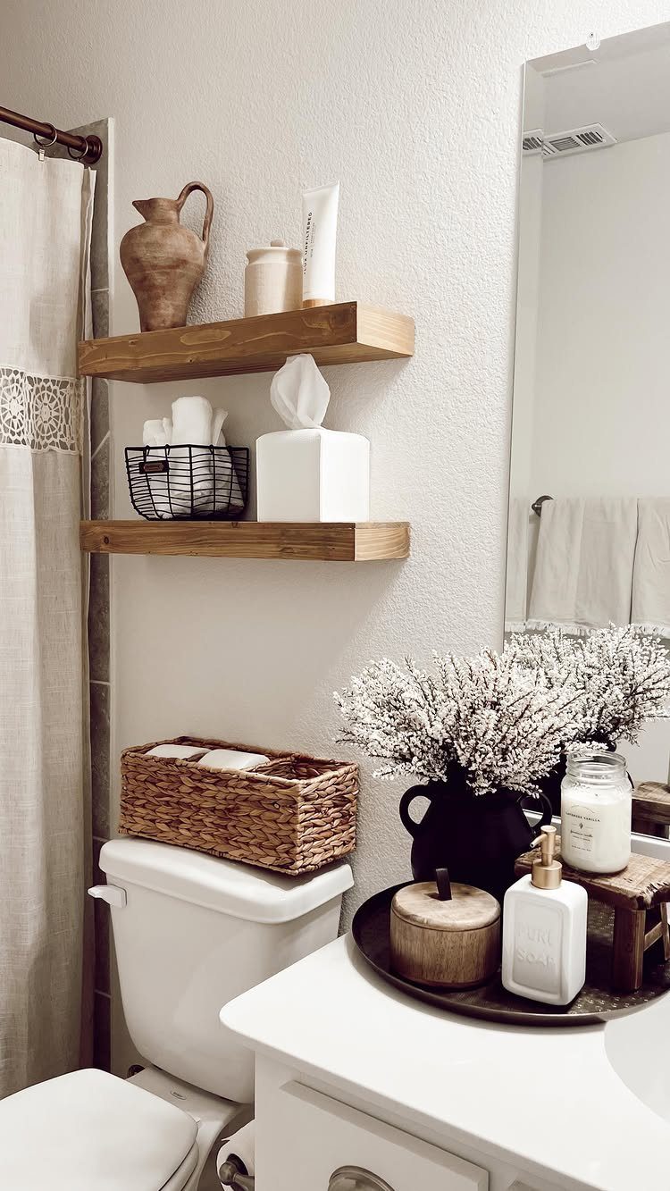 21 Bathroom Shelf Ideas That Make Tight Storage Work Harder 2 Two wooden floating shelves holding various bathroom decor items mounted on a white wall.