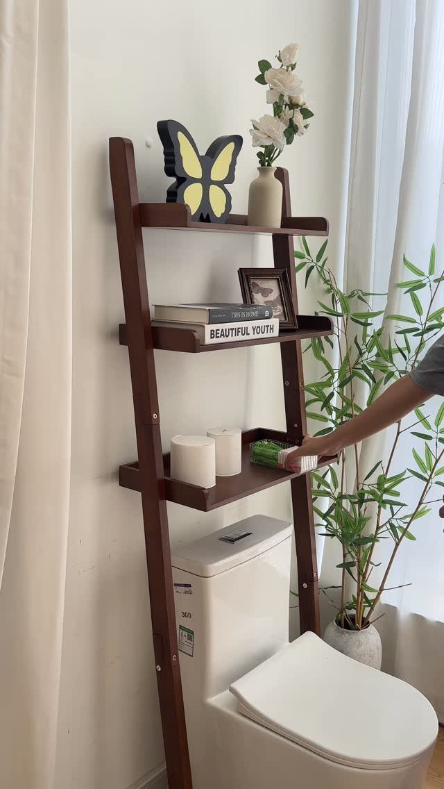 21 Bathroom Shelf Ideas That Make Tight Storage Work Harder 1 Dark wood shelving unit positioned above a white toilet holding various decorative bathroom items.