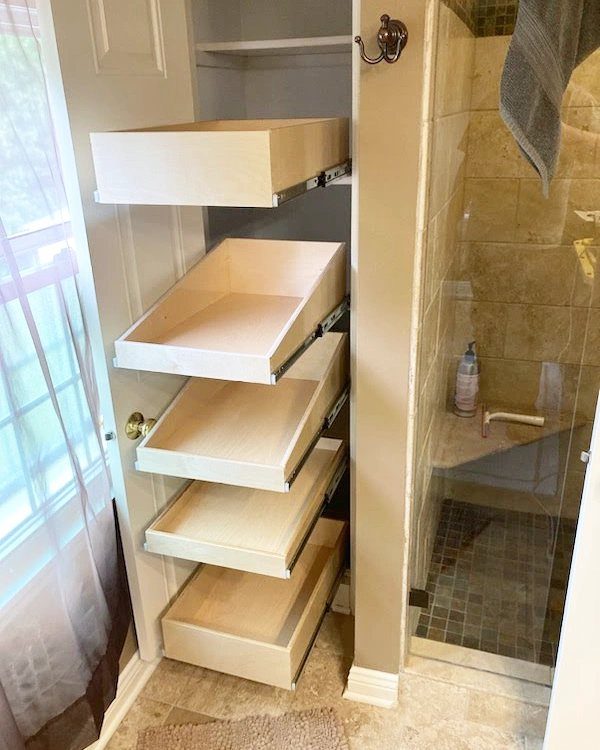 21 Bathroom Shelf Ideas That Make Tight Storage Work Harder 9 Five light wooden pull-out drawers stacked vertically in a narrow built-in storage compartment.