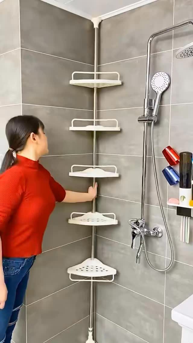 21 Bathroom Shelf Ideas That Make Tight Storage Work Harder 19 Woman reaching for a white five-tier tension pole shower caddy in a grey tiled bathroom.