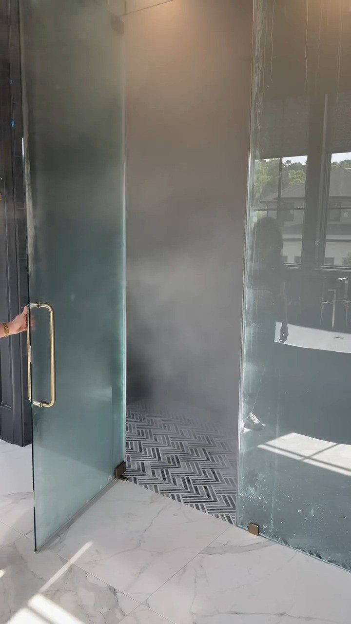 14 Bathroom Shower Ideas, From Rainfall Heads to Wet Rooms 4 Steam fills a modern shower area behind an open glass door with chevron tile flooring.