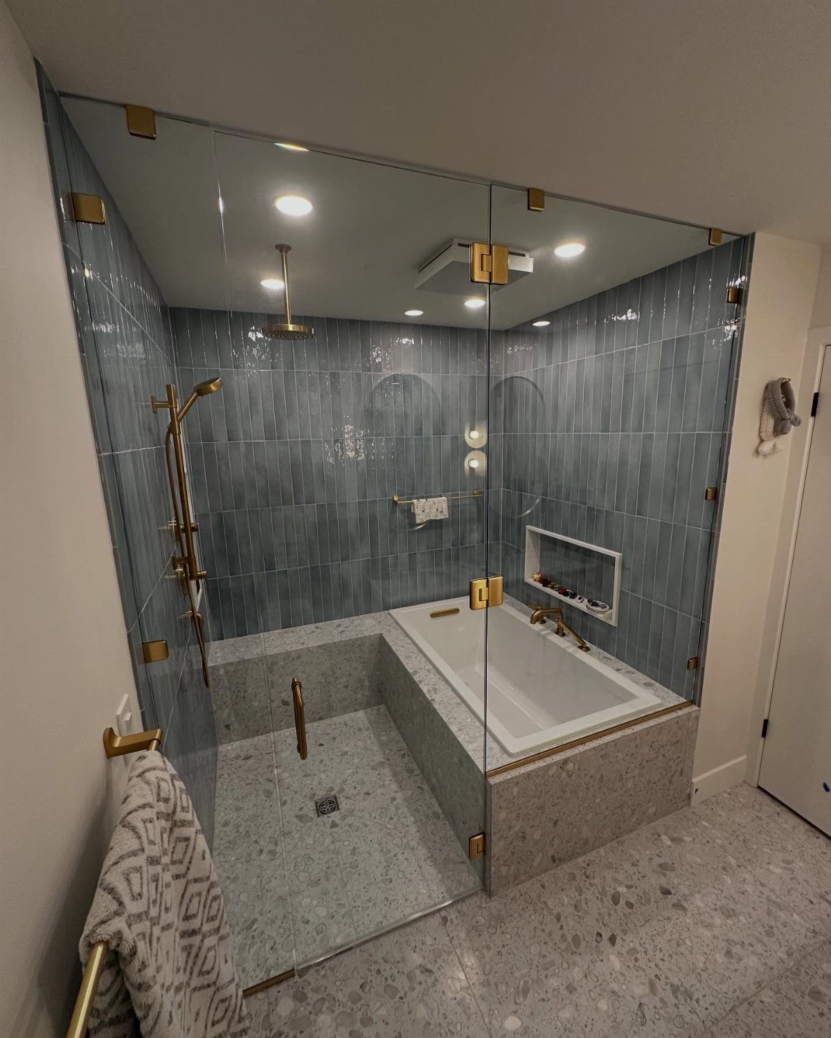 14 Bathroom Shower Ideas, From Rainfall Heads to Wet Rooms 5 A modern bathroom featuring a white bathtub combined with a walk-in shower and blue tiles.