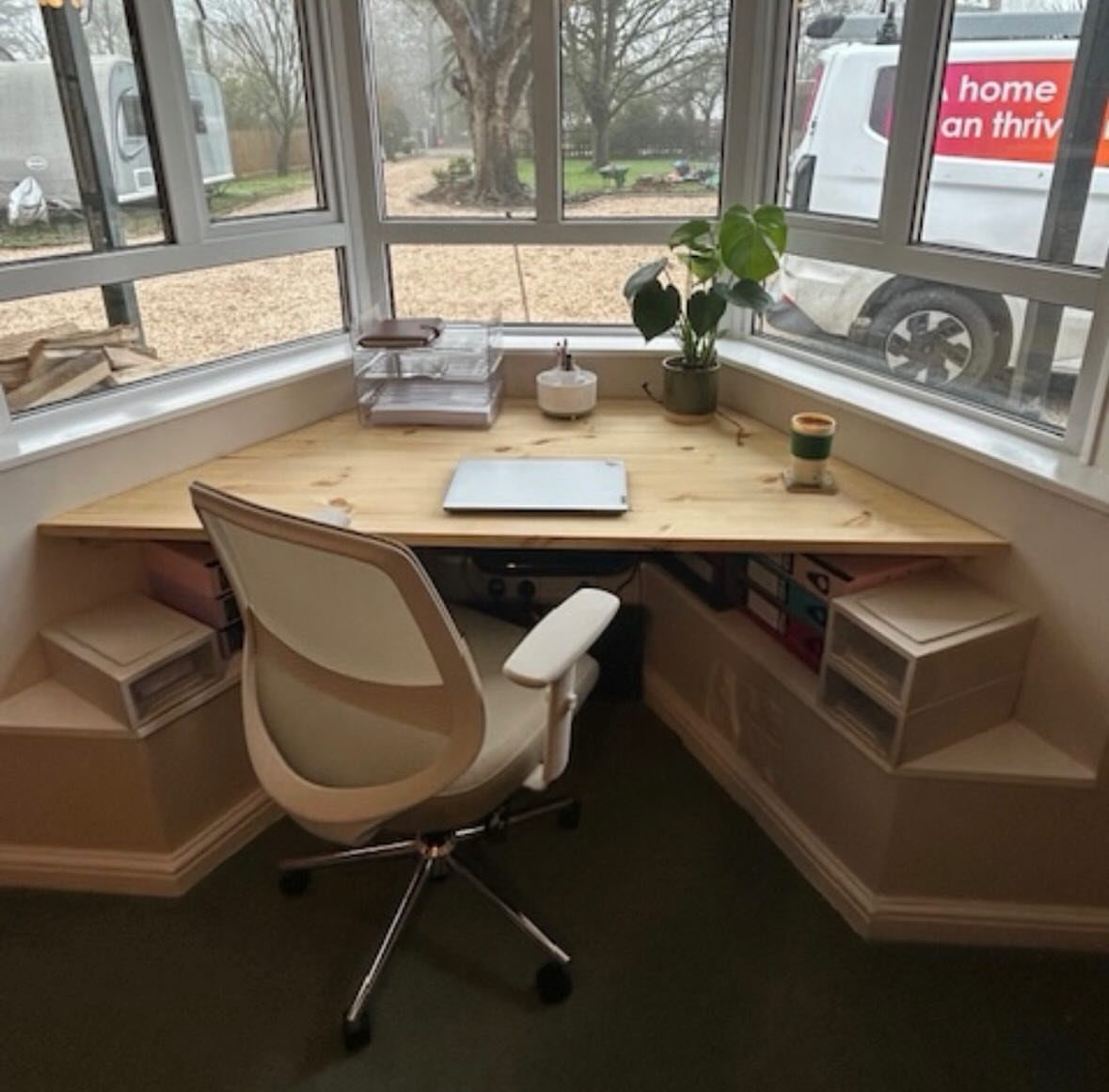 8 Bay Window Ideas for Seating, Dining, Curtains and More 5 A light wood desk built into a bay window with a white office chair.