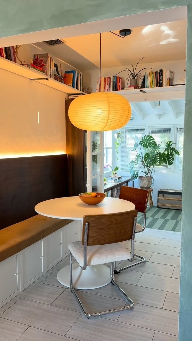 A small dining nook with a round table, modern chairs, and a built-in bench seat.