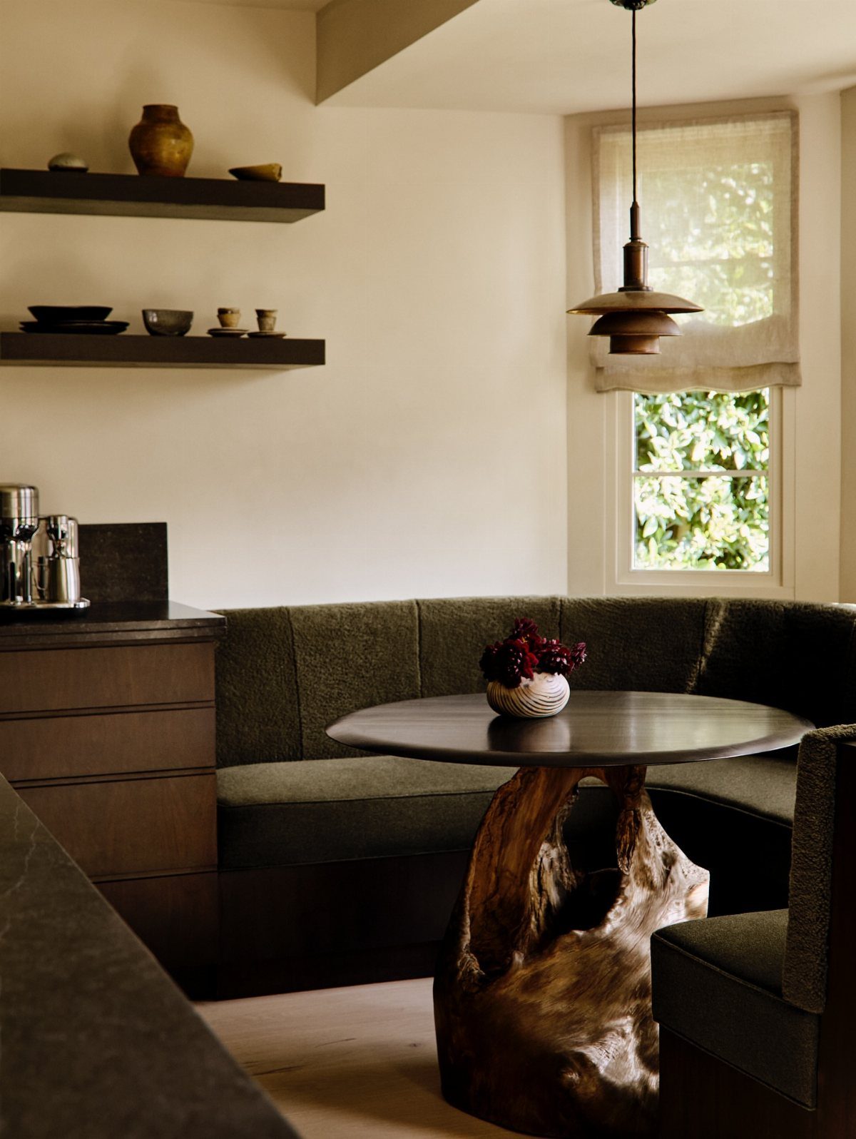 A round dining table featuring a unique sculptural tree root base in a cozy breakfast nook.
