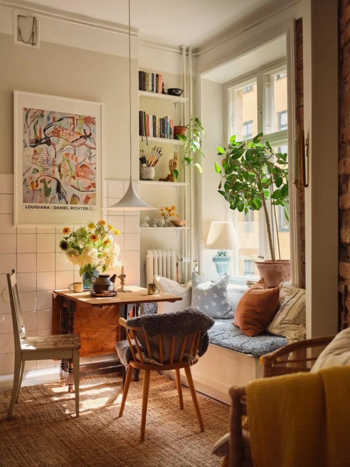 A small wooden dining table with chairs set in a sunlit breakfast nook near a window.