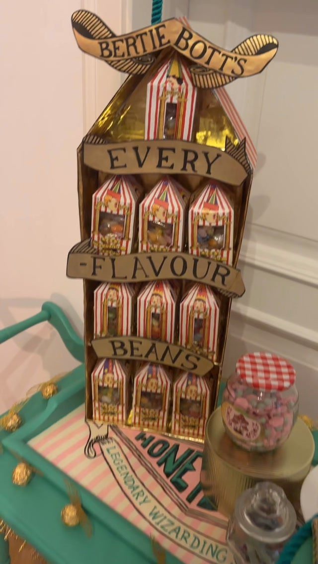 A cardboard Bertie Botts Every Flavour Beans display stand next to a jar of colorful candies.