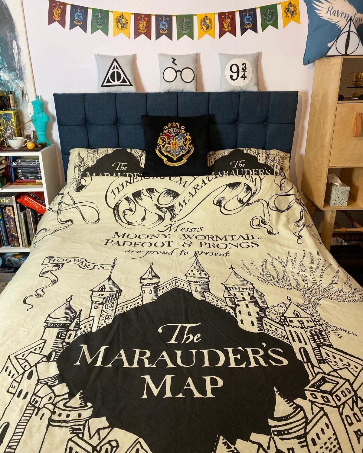A bed featuring a Marauder's Map patterned duvet cover and themed decorative pillows.