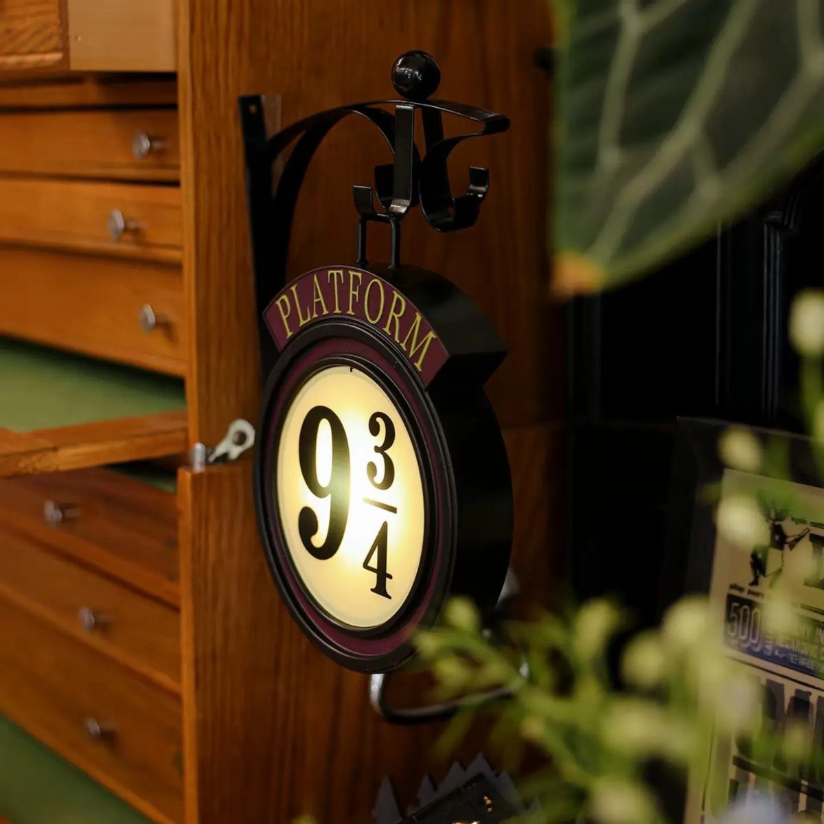 A glowing circular sign reading Platform 9 3/4 hanging from a black metal bracket.