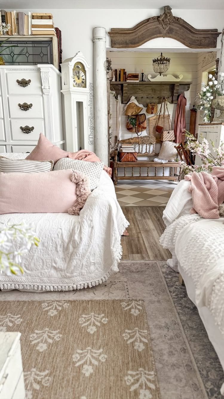 White sofas with pink pillows and patterned rugs in a rustic, cozy living room setting.