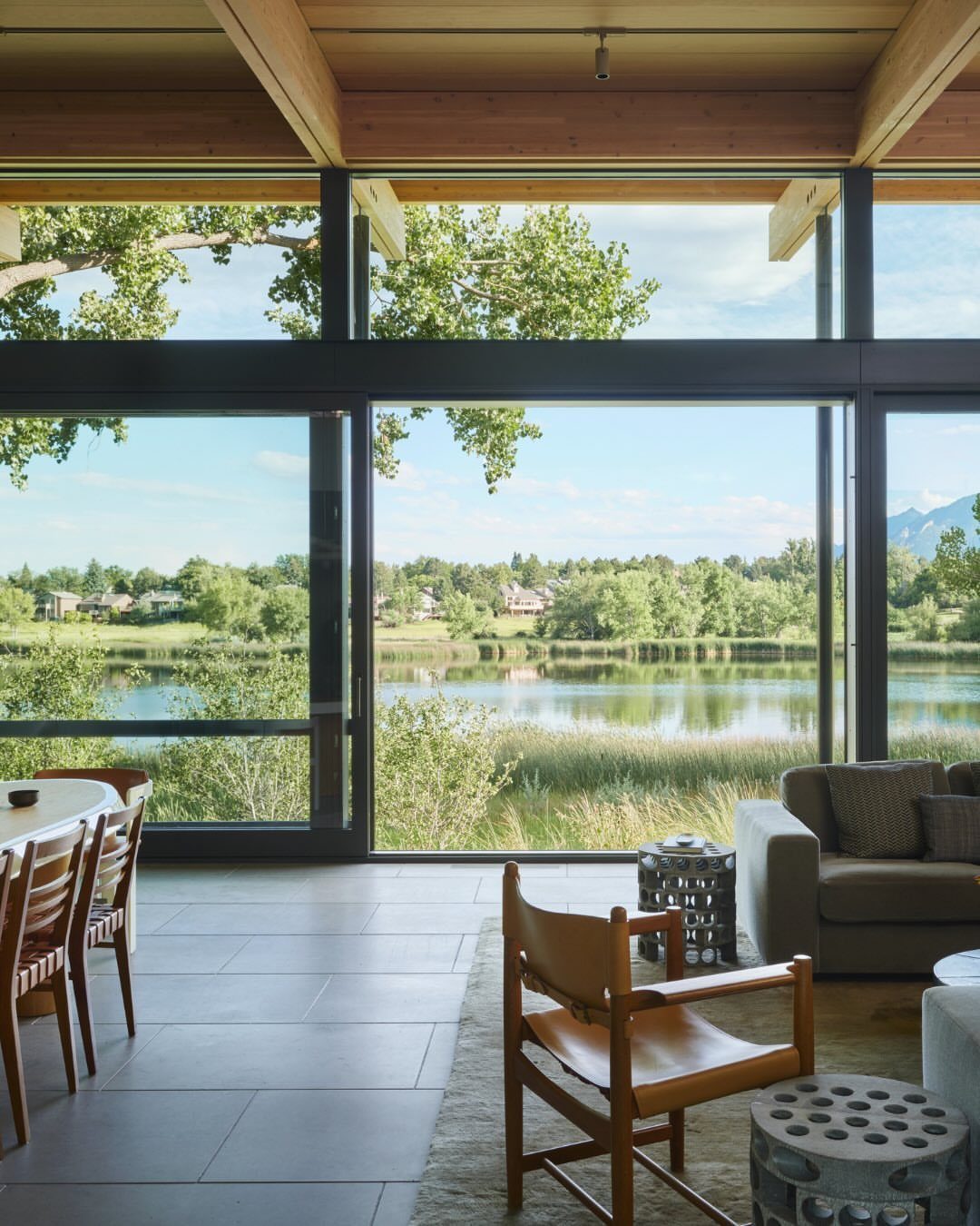 Large glass sliding doors opening from a modern living room toward a serene lake view.