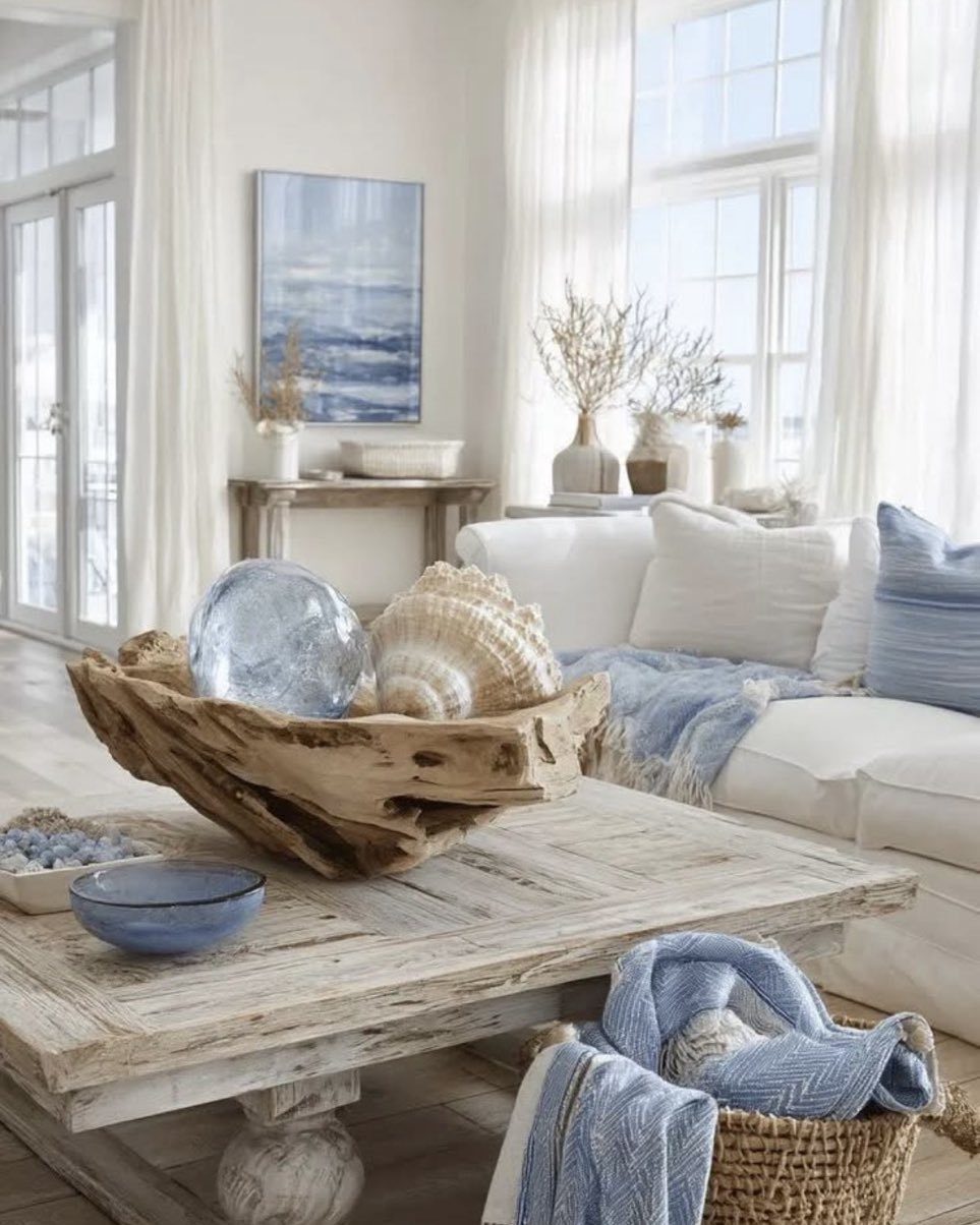 Driftwood bowl containing a glass sphere and seashell on a rustic wooden coffee table.