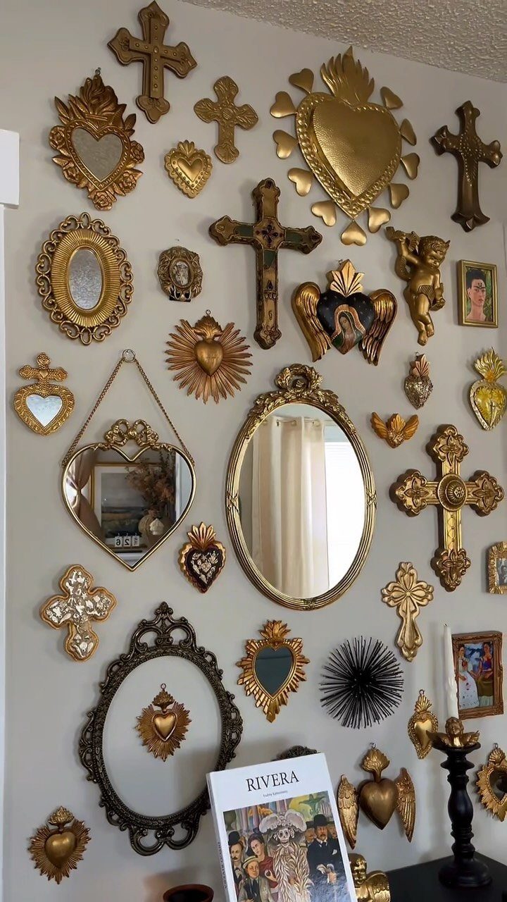 14 Mexican Decor Ideas for Every Room 11 Gold religious crosses, sacred hearts, and ornate mirrors arranged on a white wall.