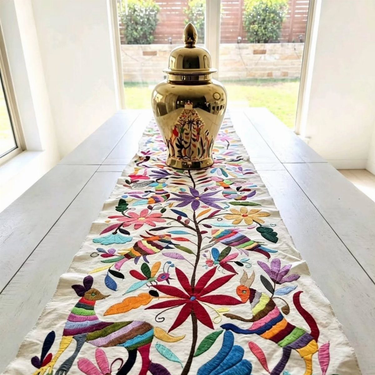 14 Mexican Decor Ideas for Every Room 4 Embroidered table runner with colorful floral and animal patterns on a white dining table.