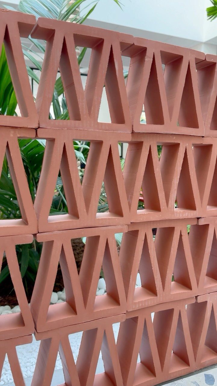14 Mexican Decor Ideas for Every Room 9 Terracotta geometric bricks forming a decorative screen with green plants visible through the openings.
