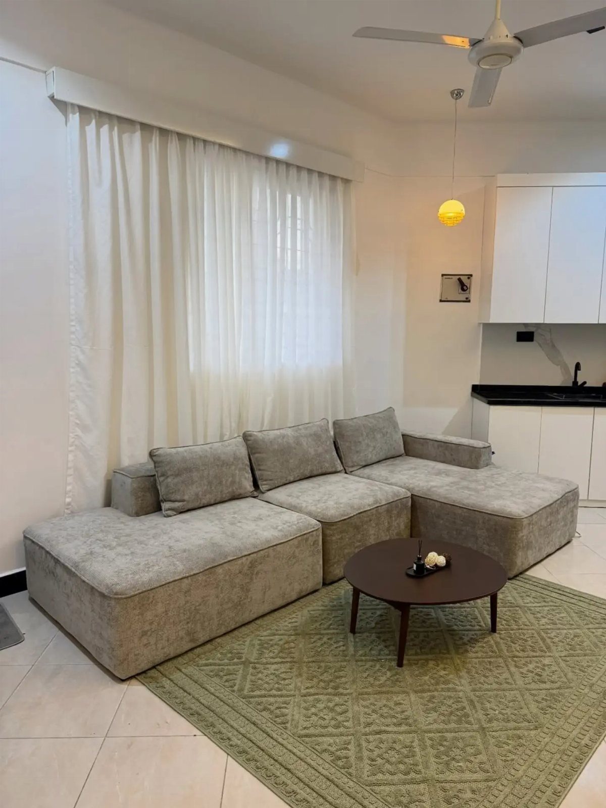 A grey modular sectional sofa arranged in a living room with a green rug.