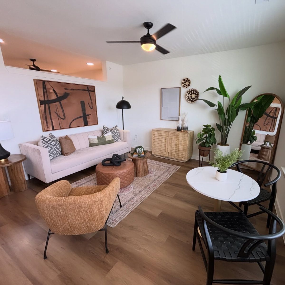 A modern living room with a pink sofa, textured pillows, a woven chair, and a patterned rug.