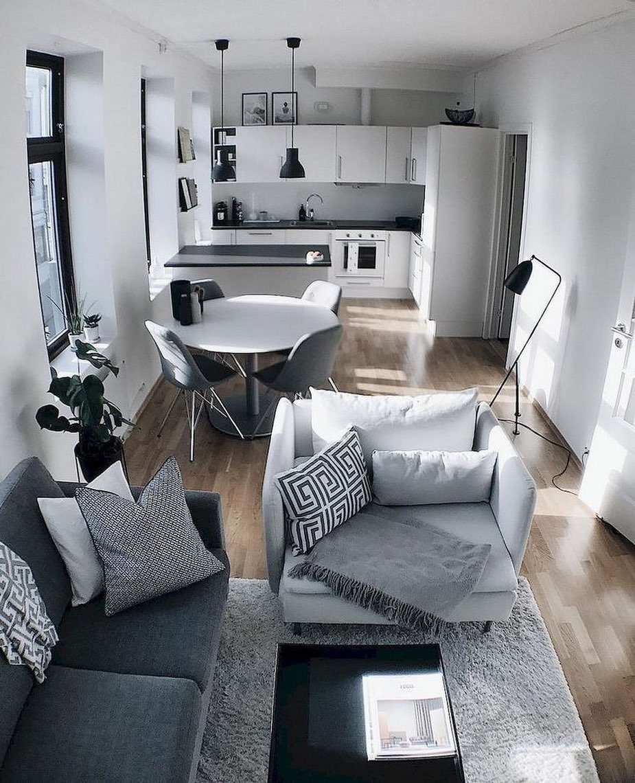 Grey sofa and armchair arranged in a small living area near a dining table and kitchen.