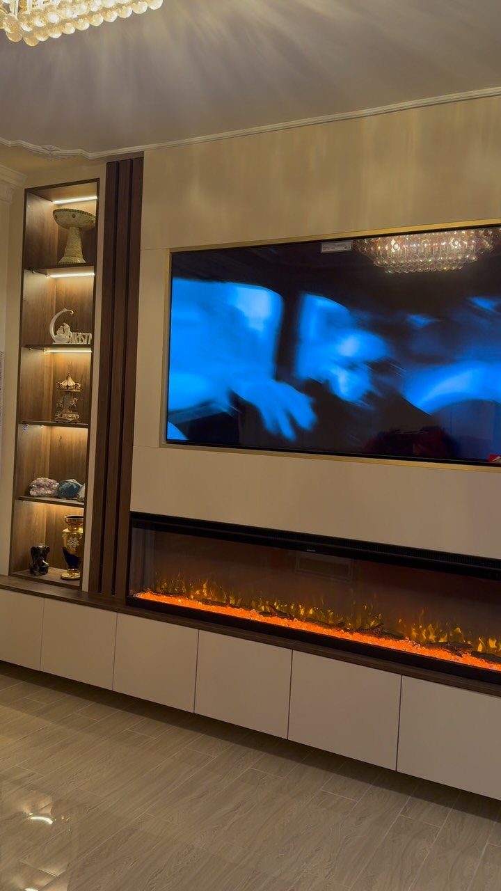 A large wall-mounted television sits above a modern built-in entertainment unit with an electric fireplace.