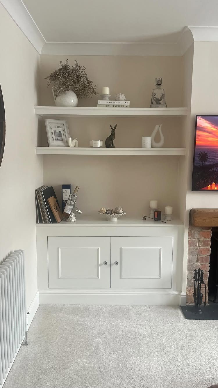Built-in white shelving and cabinetry in a neutral colored living room alcove.