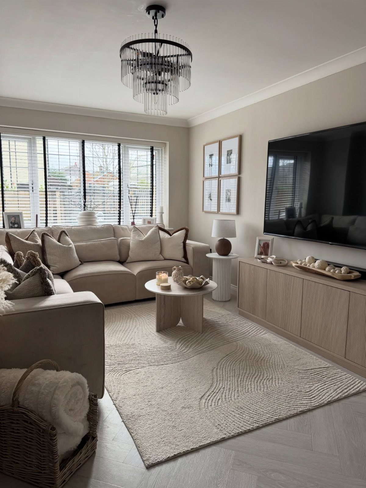 Beige sectional sofa and coffee table in a small living room with a large television.