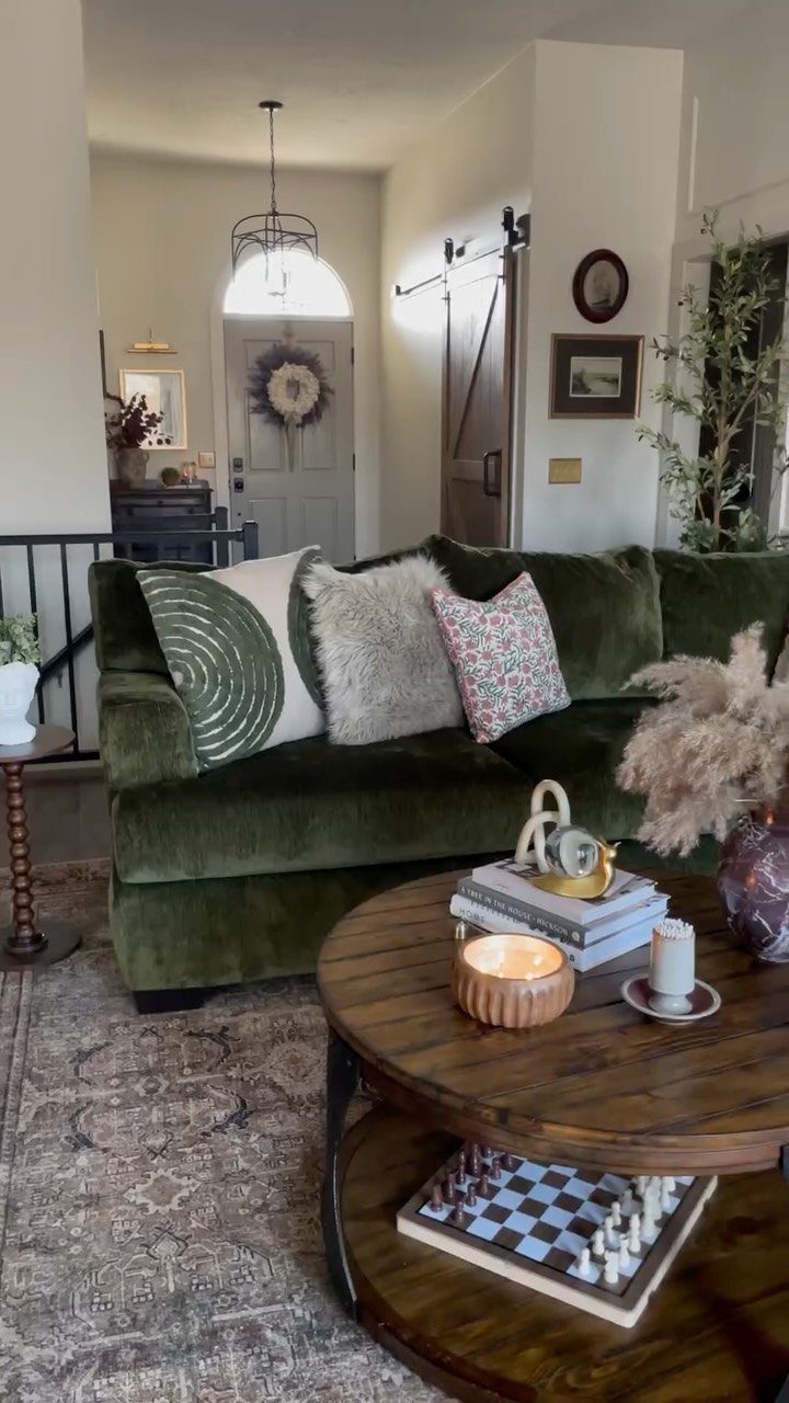 A dark green velvet sofa with decorative pillows sits behind a wooden coffee table.