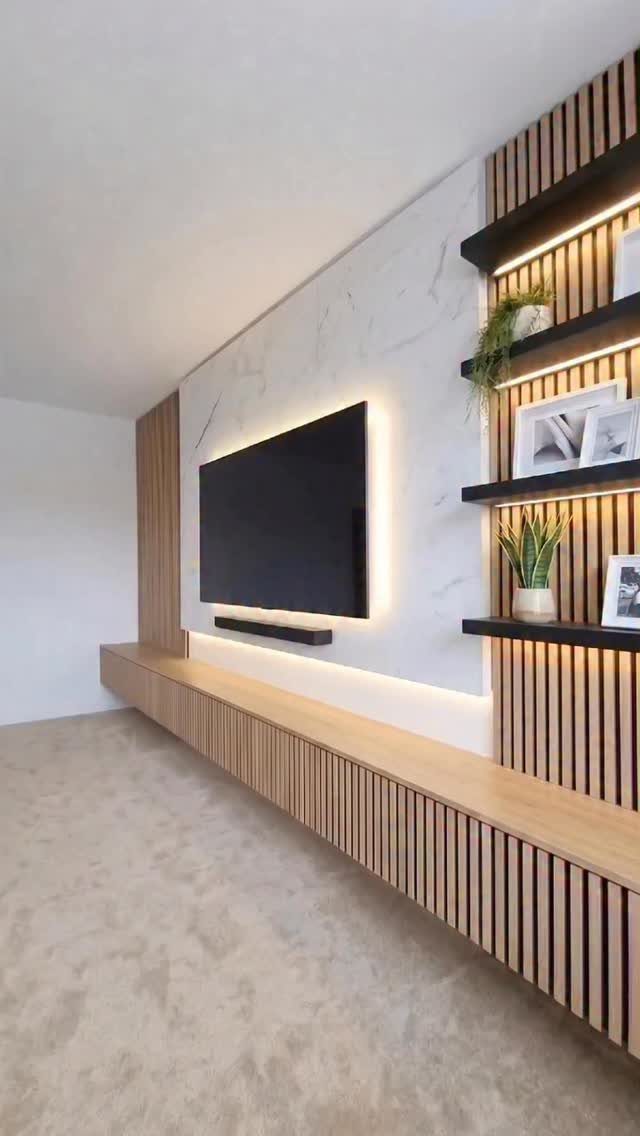 A modern media wall with a marble TV panel, LED lighting, and wooden slatted shelving.