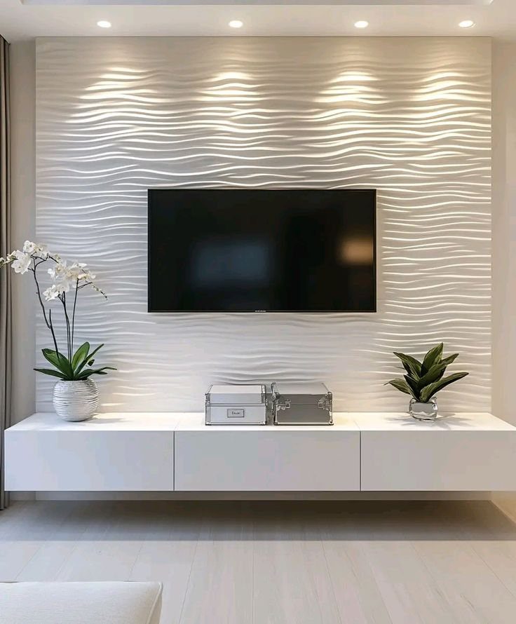 A black television mounted on a white wavy textured accent wall above a floating console.