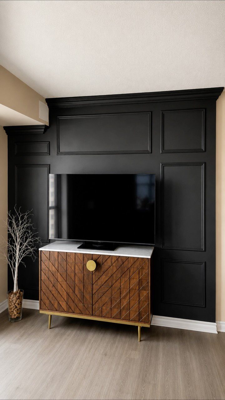Black wall with decorative frame molding panels behind a television and wooden sideboard.